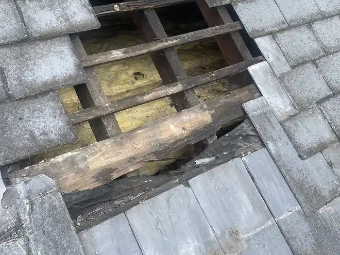 Roof repair — before, slate tiles off, rafters and insulation exposed